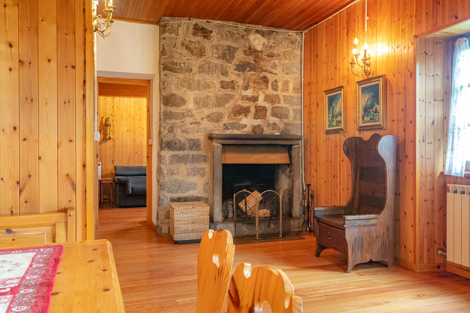 Una sala revestida de madera con una chimenea de piedra y asientos de madera.
