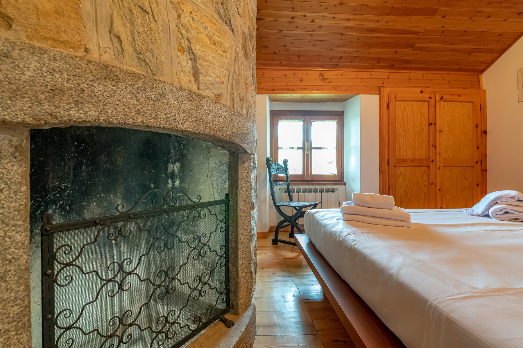 Un dormitorio con una gran chimenea de piedra junto a la cama.