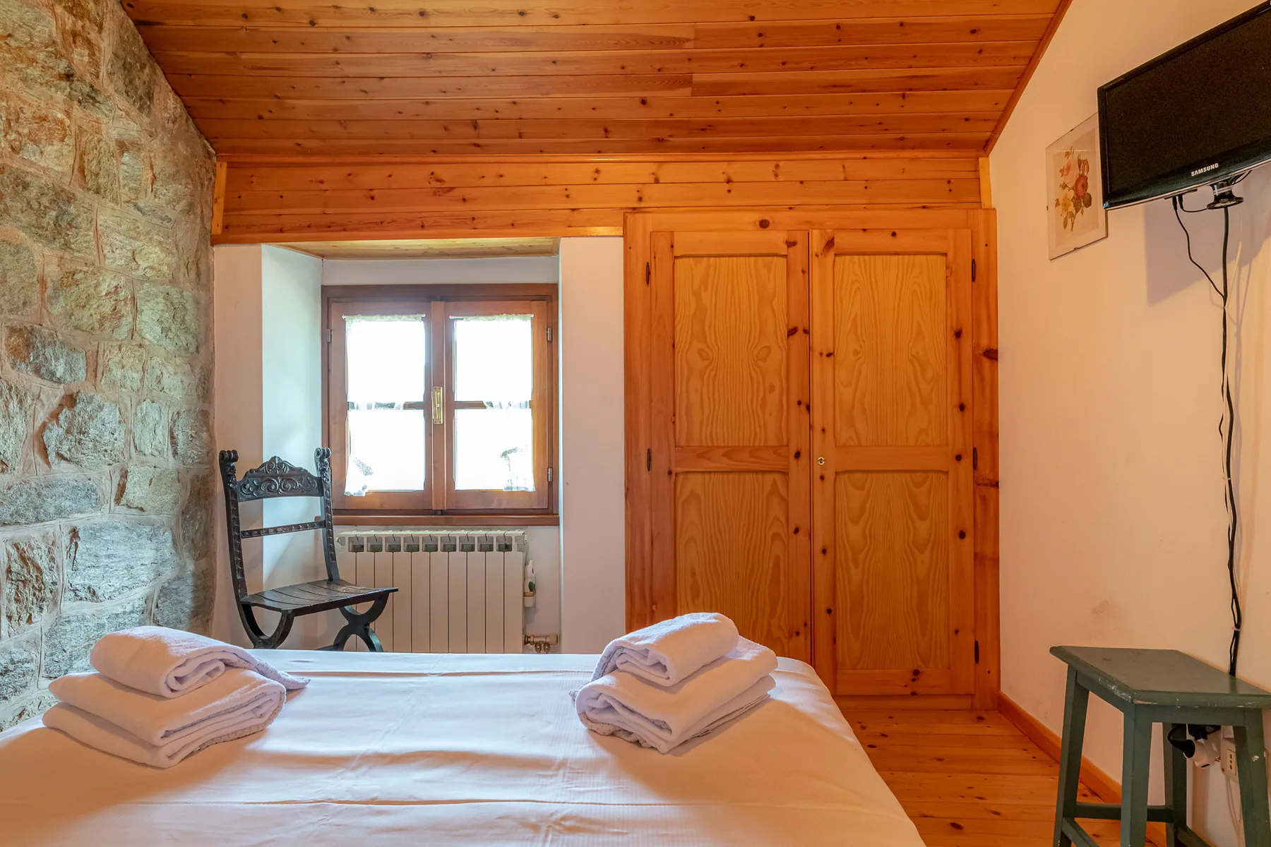Un dormitorio con techo de madera, una cama y un armario.