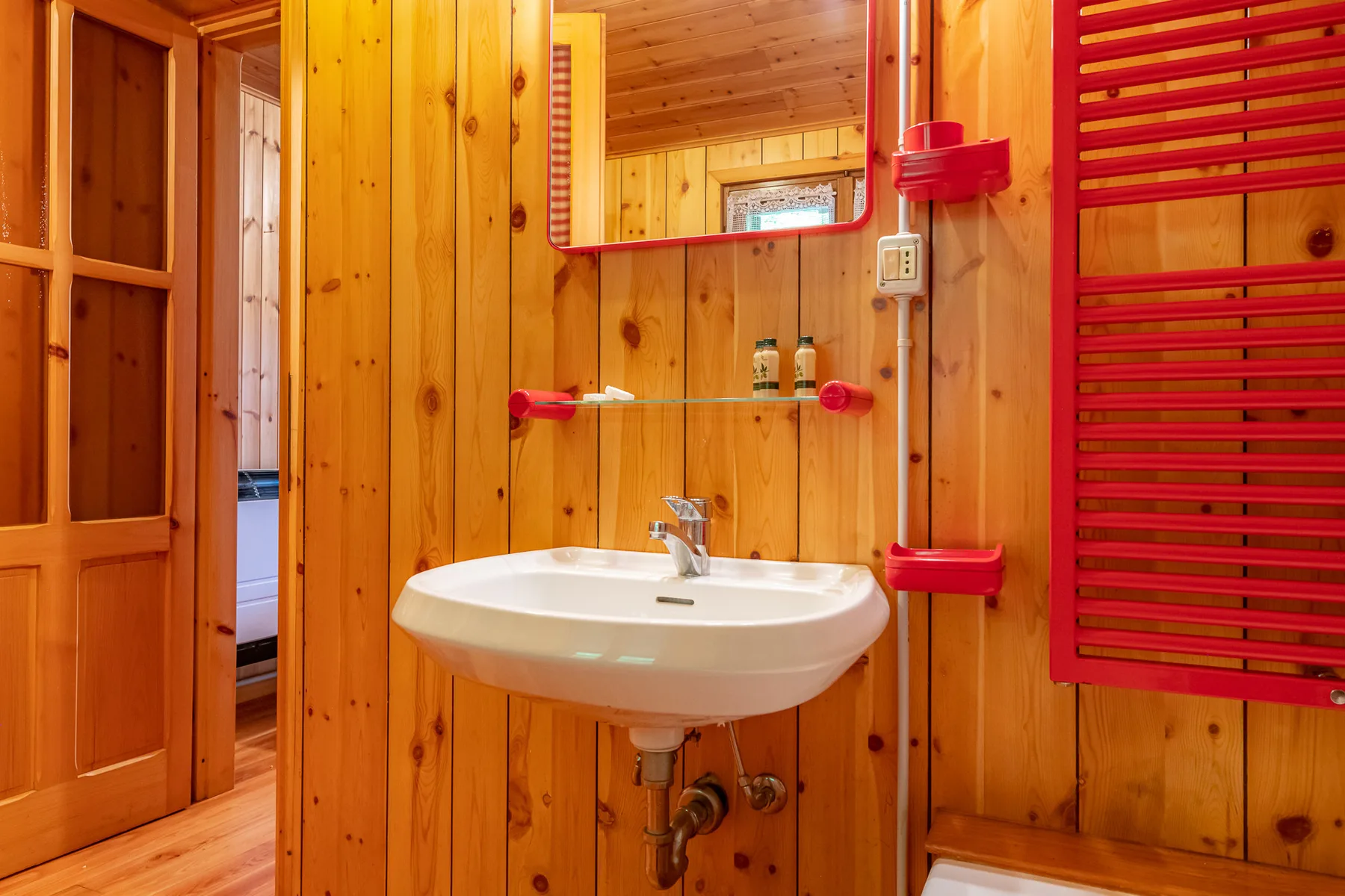 Un baño revestido de madera con un lavabo blanco y un espejo.