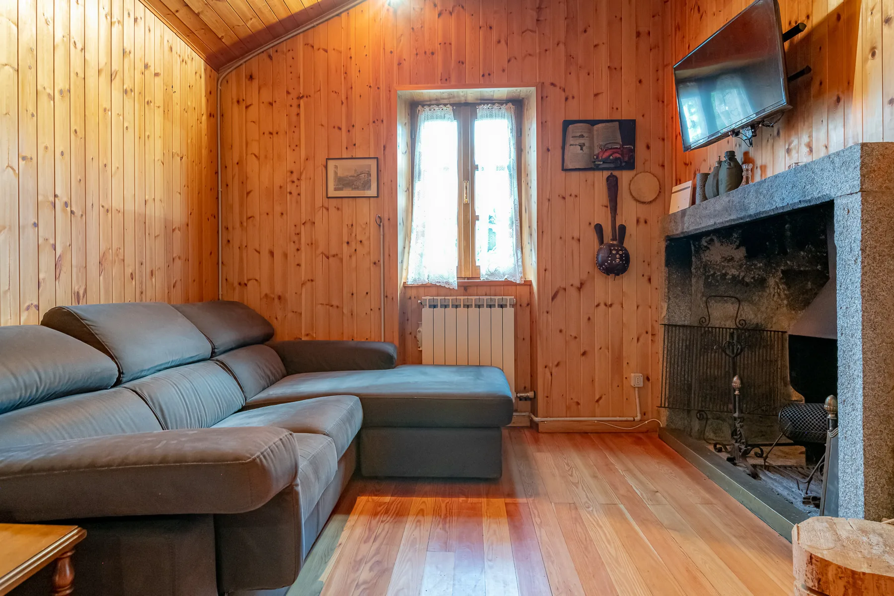 Una sala de estar revestida de madera con sofá seccional y chimenea.