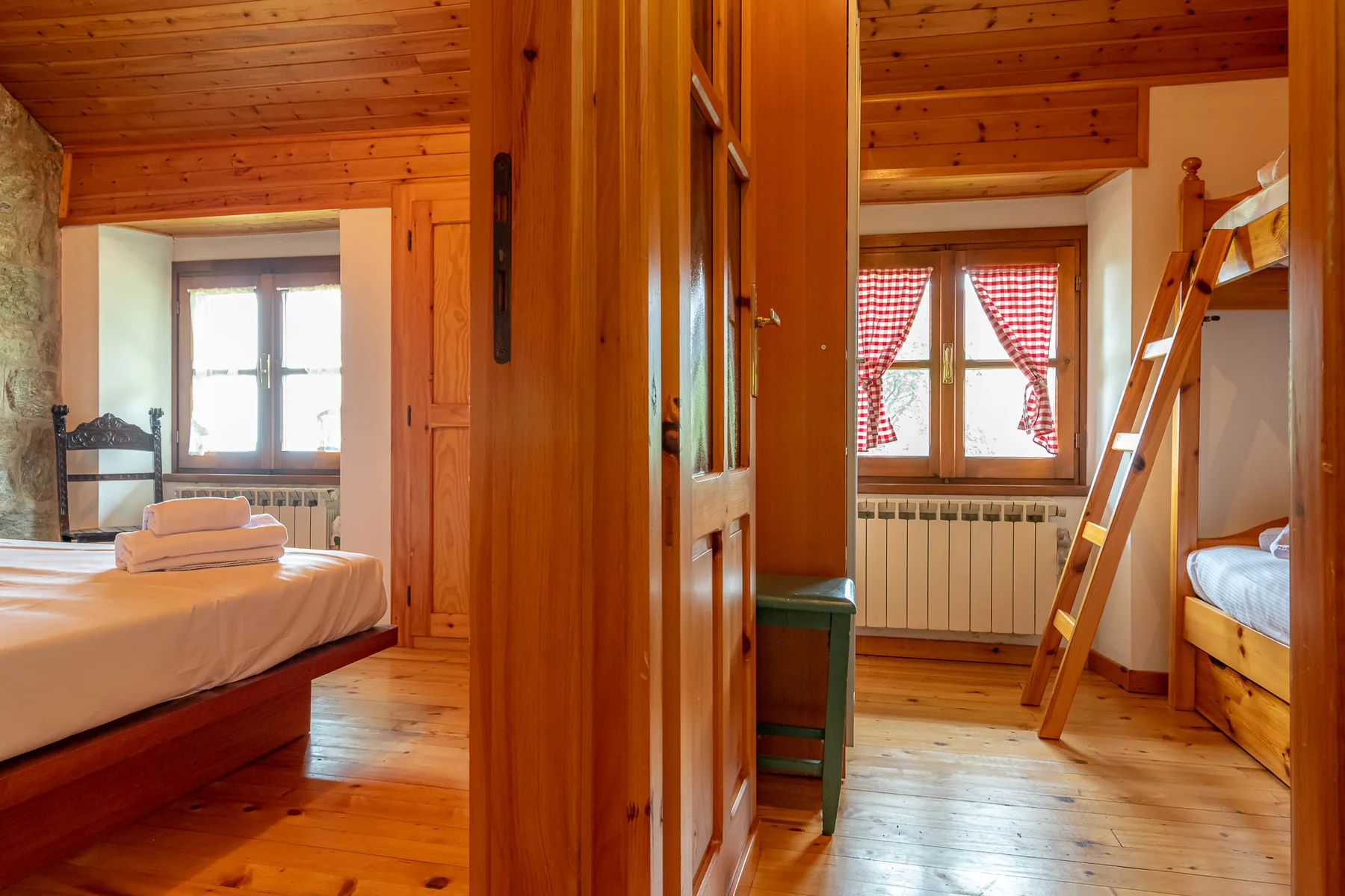 Un dormitorio revestido de madera con camas, una ventana y una escalera.