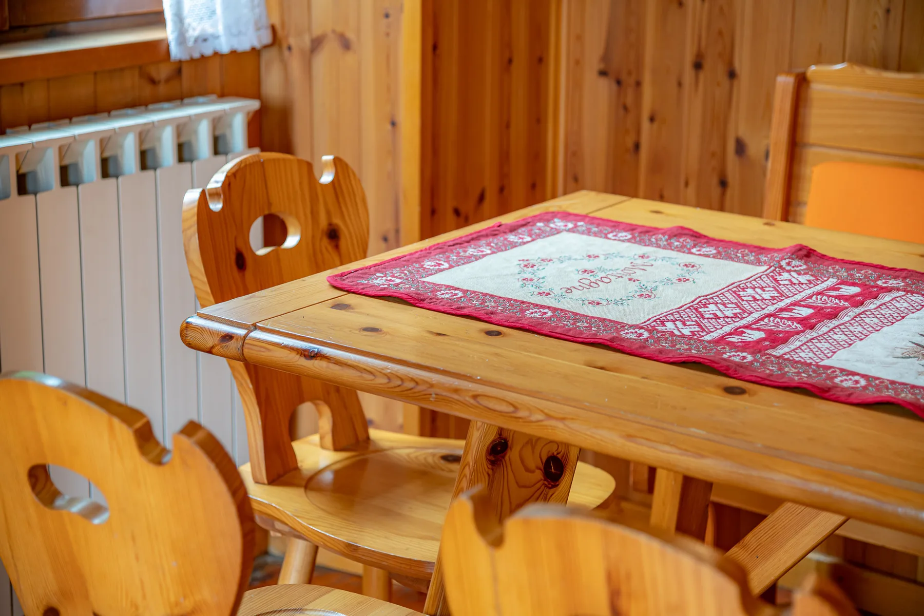 Comedor de madera con una mesa cubierta por un mantel estampado rojo.