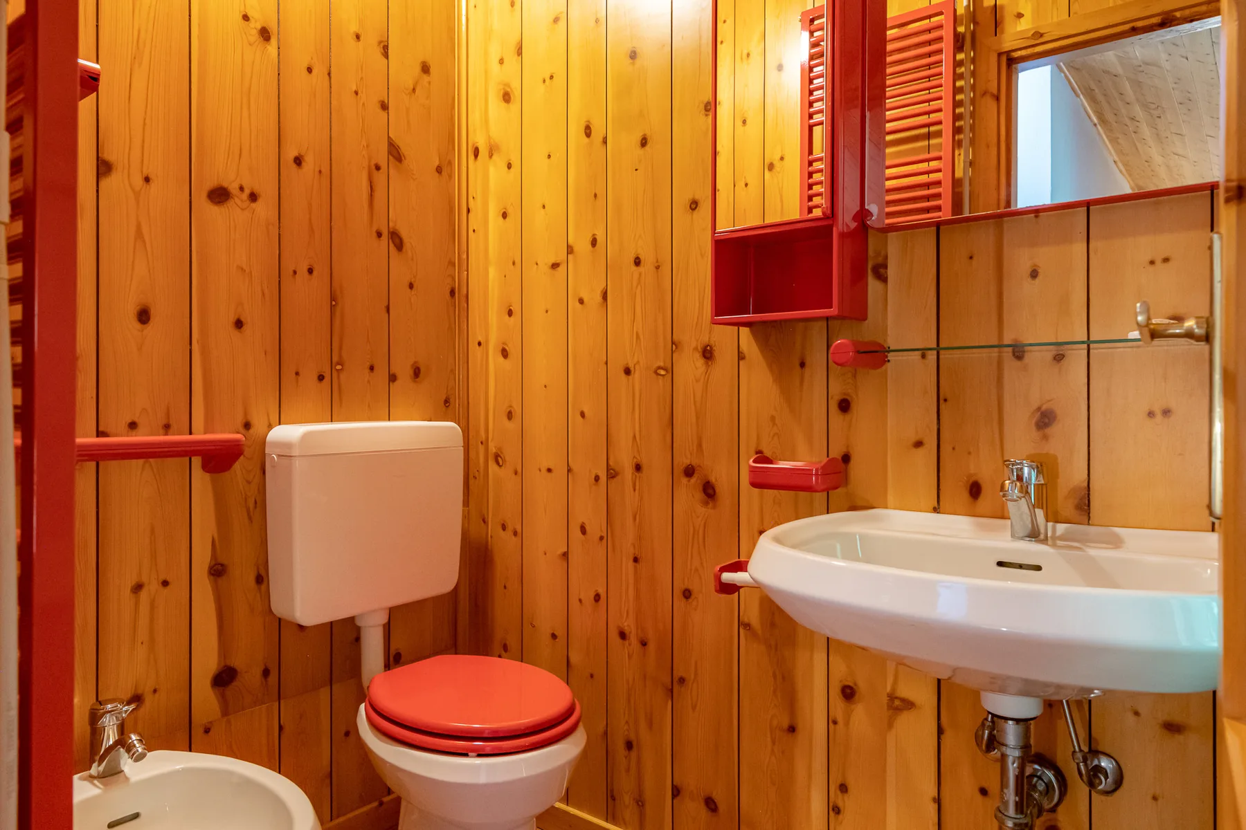 Un baño revestido de madera con inodoro, lavabo y bañera.