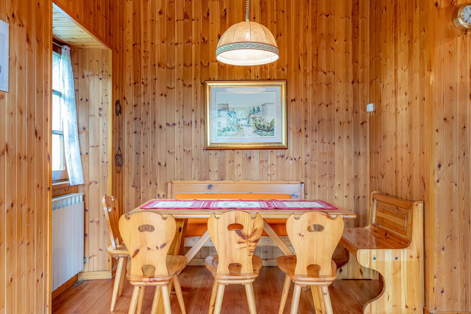 Un comedor revestido de madera con una mesa y sillas bajo una lámpara colgante.