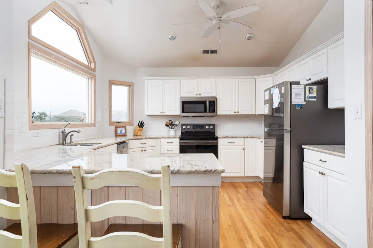 A bright kitchen with white cabinets, a central island, and stainless steel appliances.