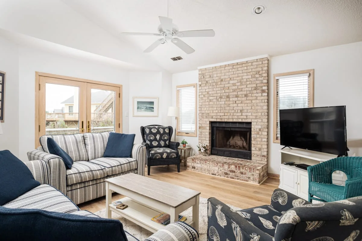 A bright living room with striped seating, a fireplace, and a television.