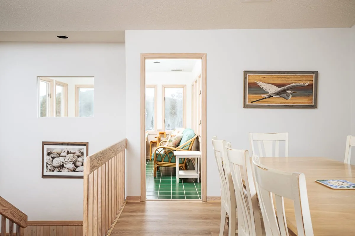 Comedor con una mesa de madera clara y sillas junto a una puerta abierta.