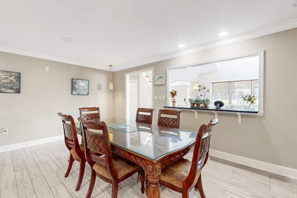 A dining room with a glass-topped wooden table and seating.