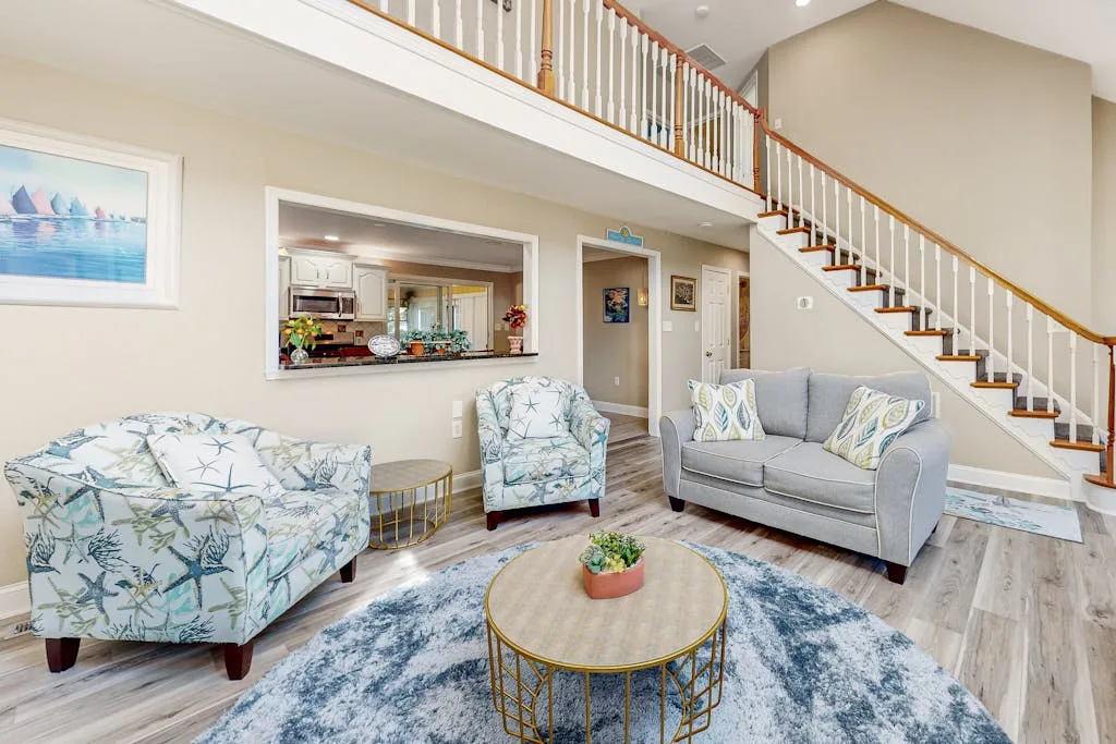 A living room with seating, a round coffee table, and a staircase.