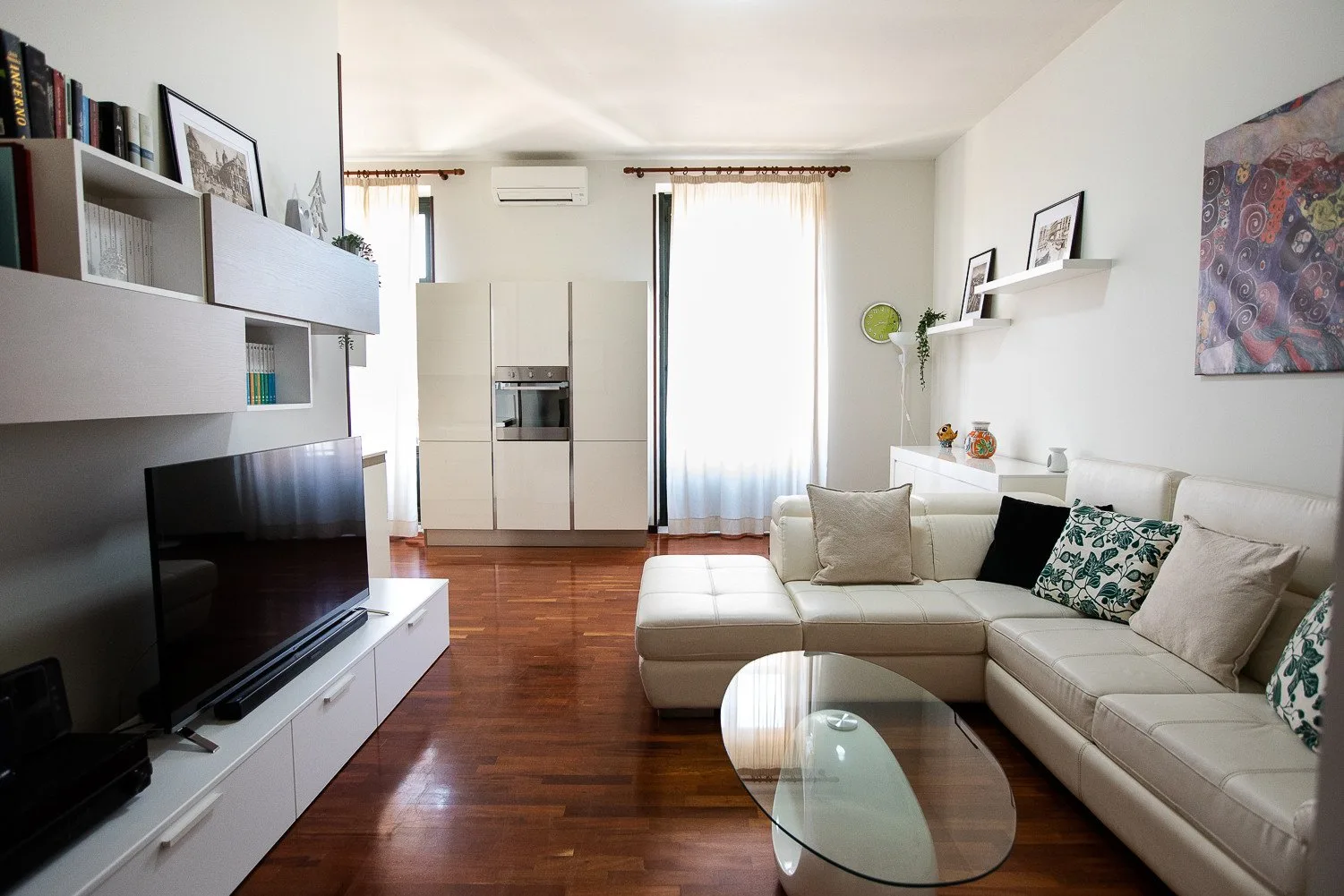 Una sala luminosa con asientos, un televisor y una mesa de centro de cristal.