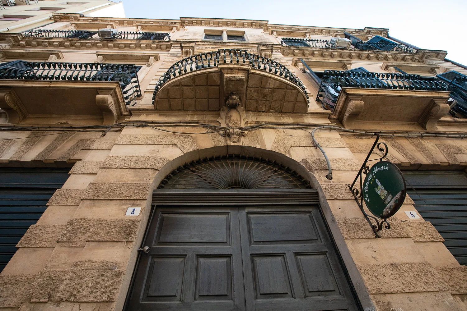 Una fachada de piedra con una entrada oscura en arco y balcones arriba.