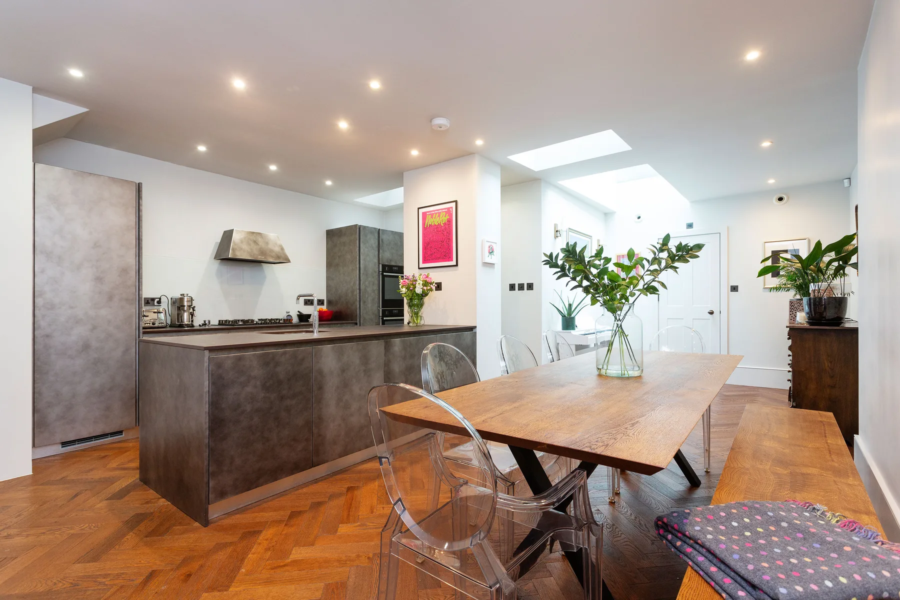 An open kitchen and dining area with a wooden table and bright skylight.