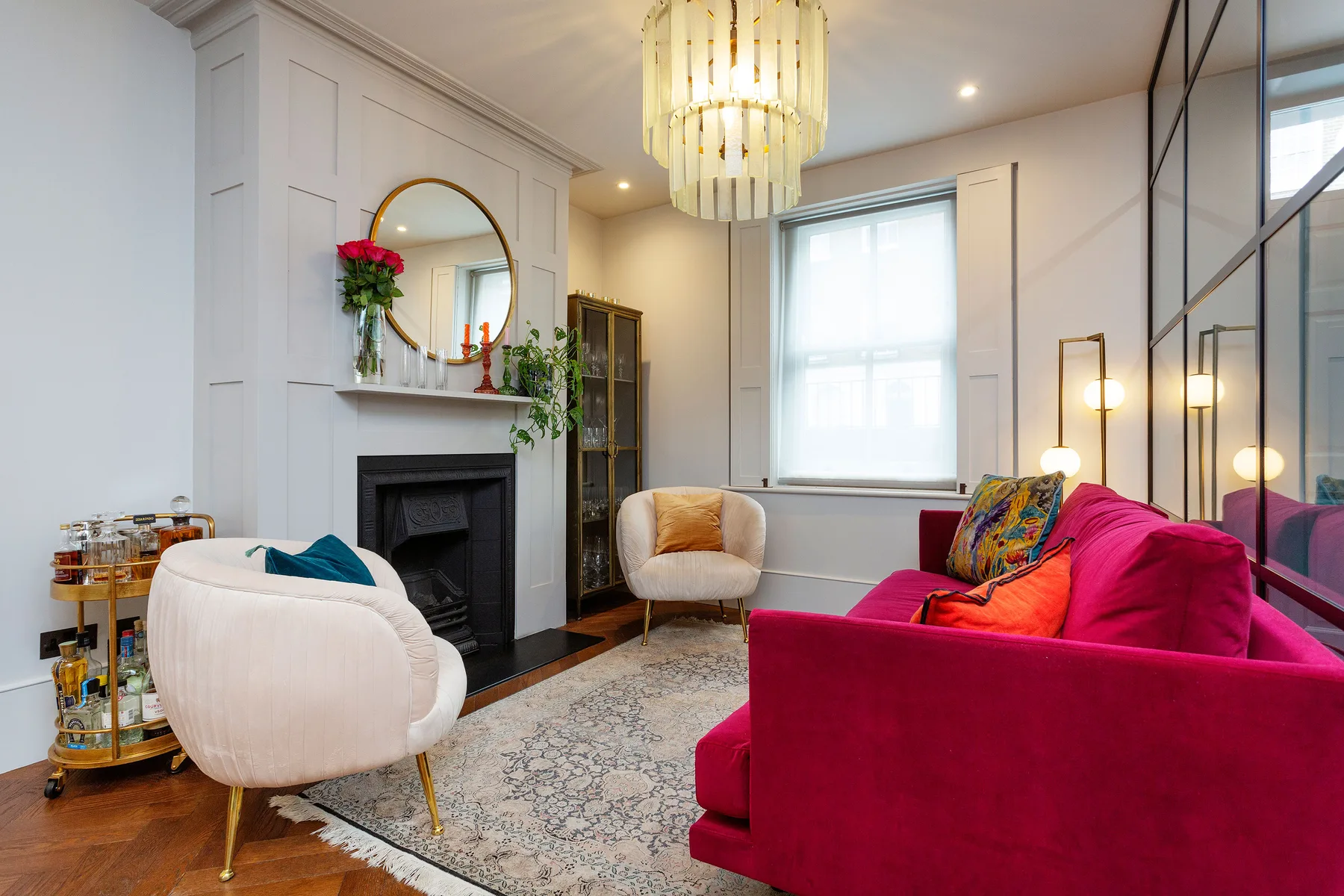 A living room with bright pink seating, a fireplace, and a patterned rug.