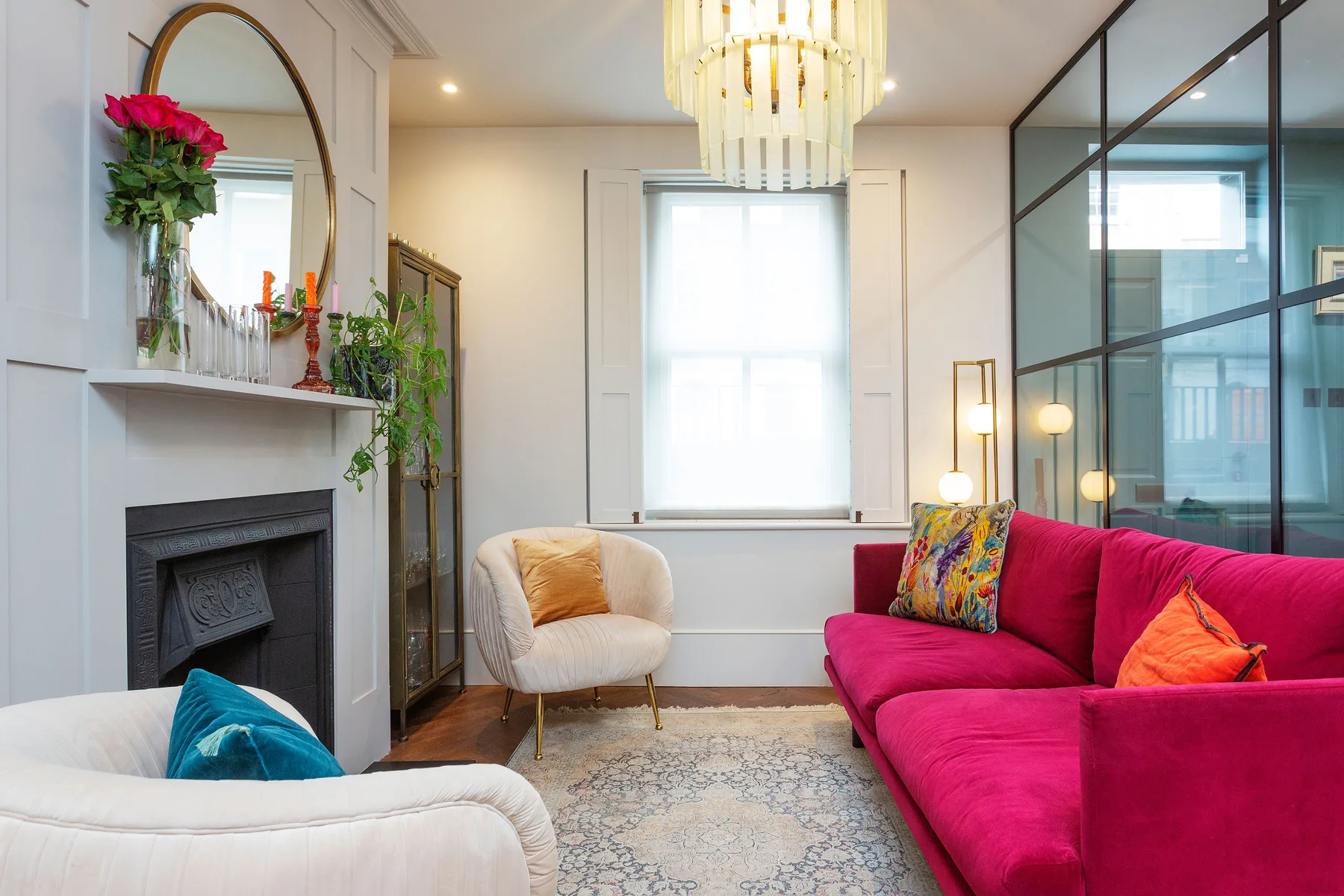 A bright living room with colorful seating, a fireplace, and a large window.