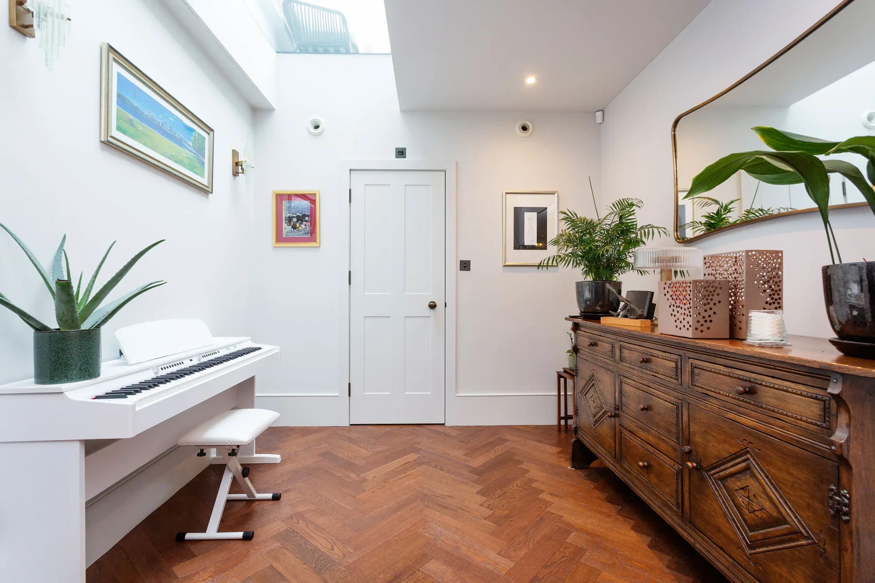 A bright room with a keyboard, wooden dresser, and plants.