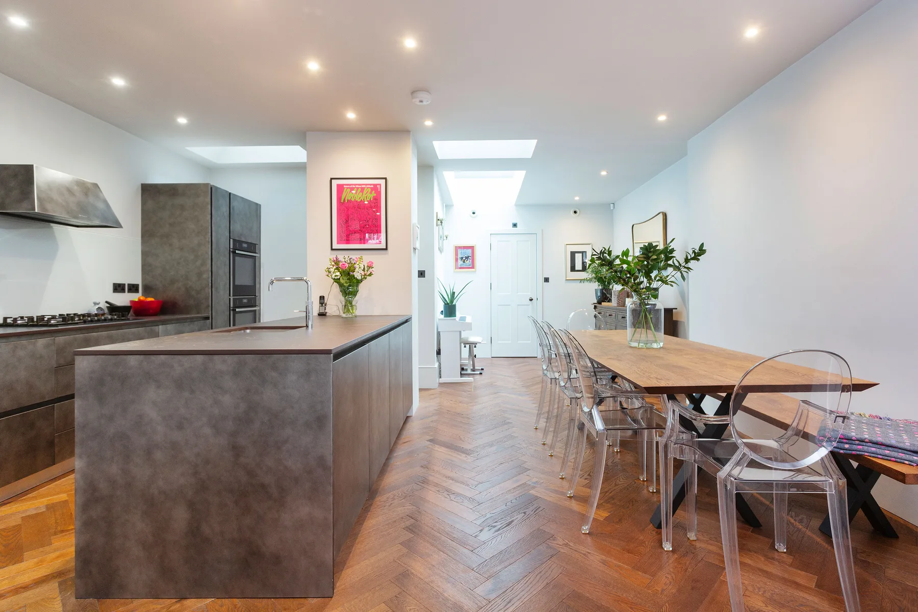 A modern kitchen and dining area with a long wooden table and clear seating.
