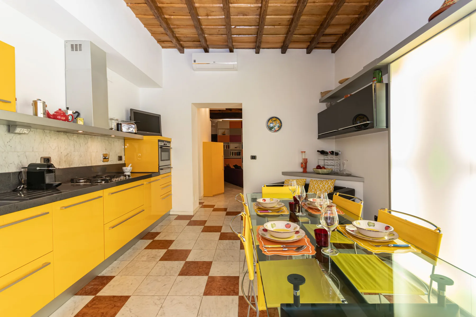 A bright kitchen and dining area with yellow cabinetry and a set table.