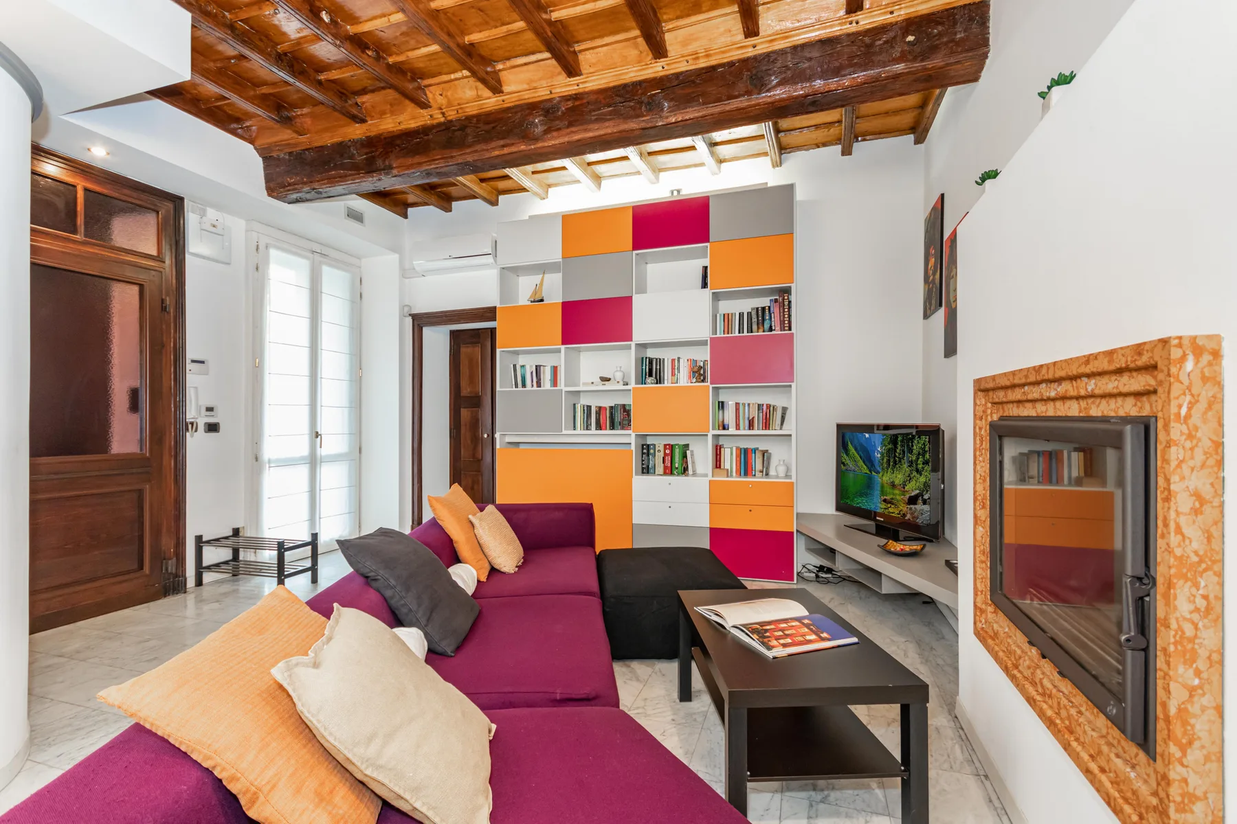 A colorful living room with a sectional seating area and built-in bookshelves.