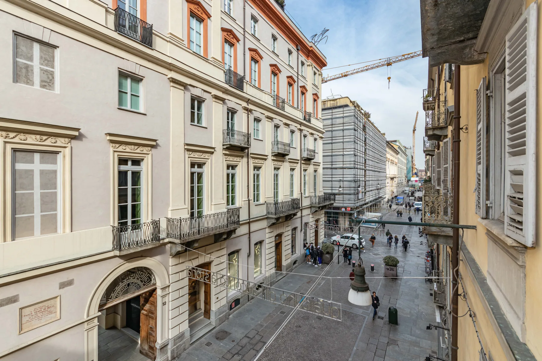 A city street lined with multi-story buildings, with pedestrians walking below.