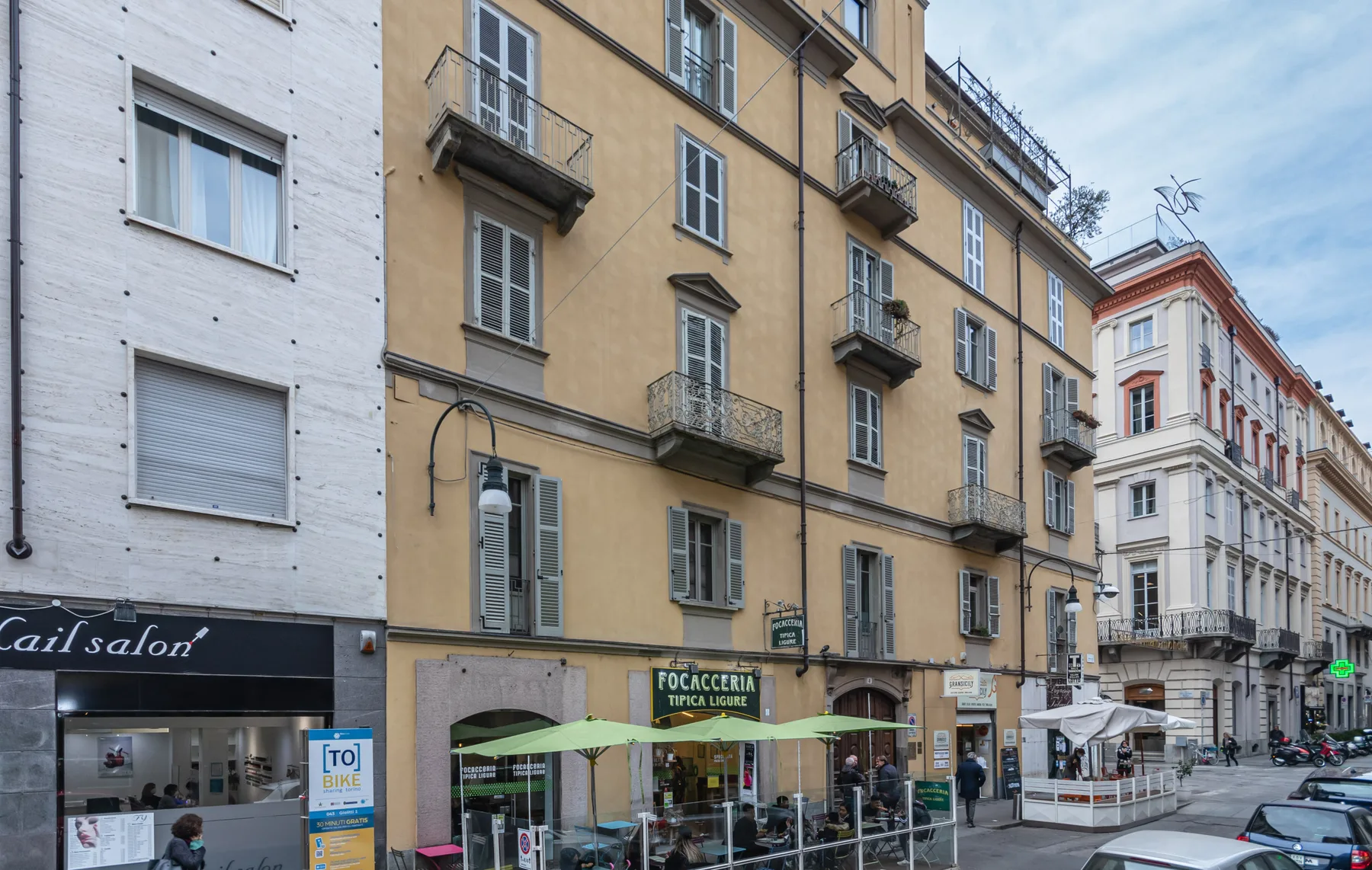 A city street lined with multi-story buildings and ground-floor shops.