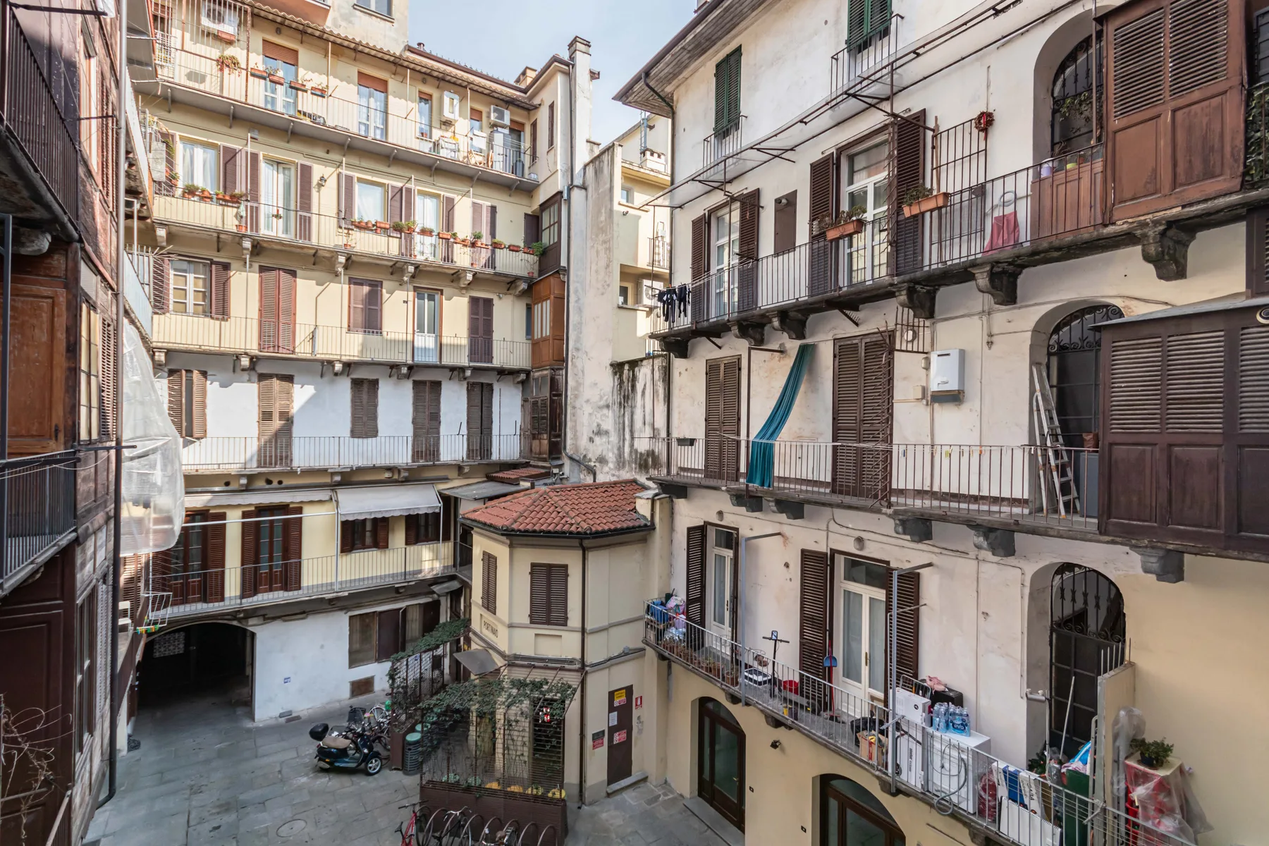 An enclosed courtyard is surrounded by residential apartment buildings with balconies and shutters.
