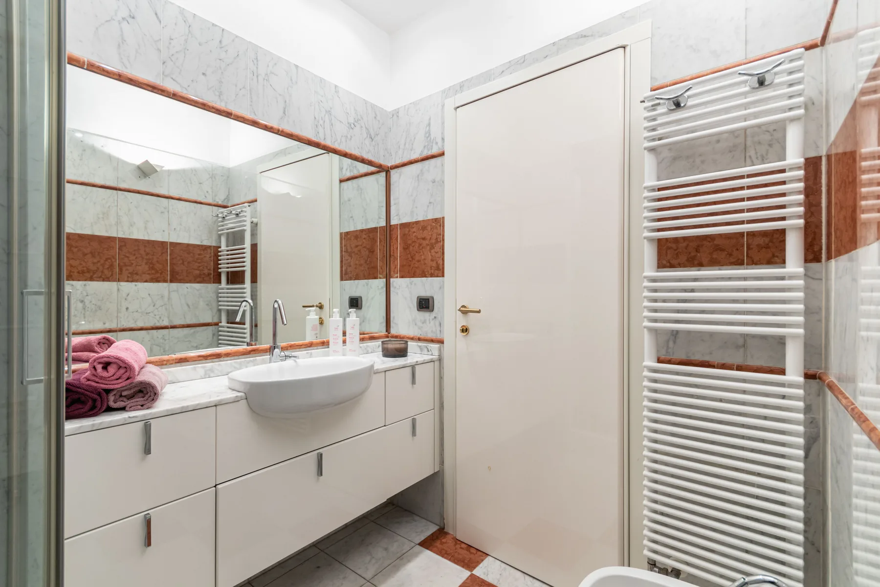 A bathroom with a sink, mirror, and wall-mounted towel radiator.
