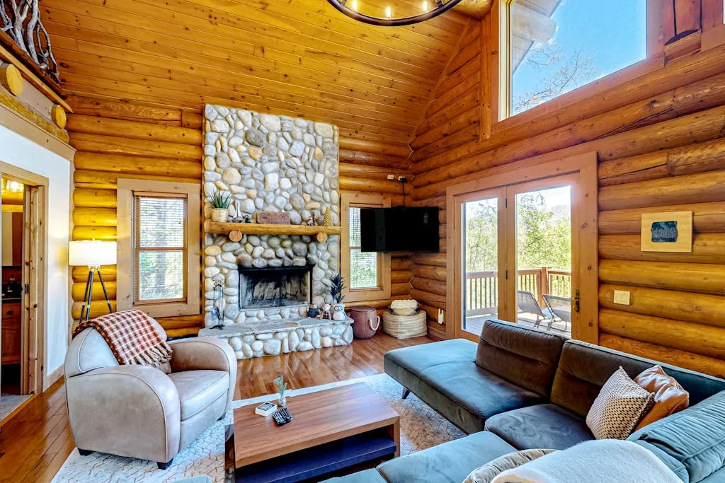 A log-walled living room with a stone fireplace and seating.