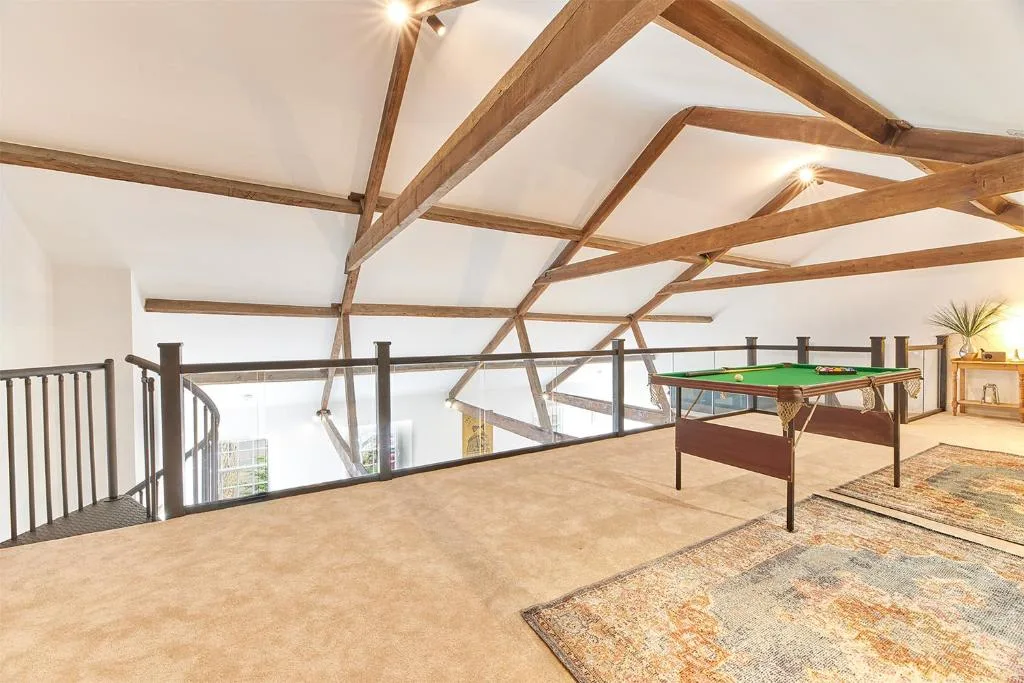 A loft recreation area with a pool table and exposed wooden ceiling beams.