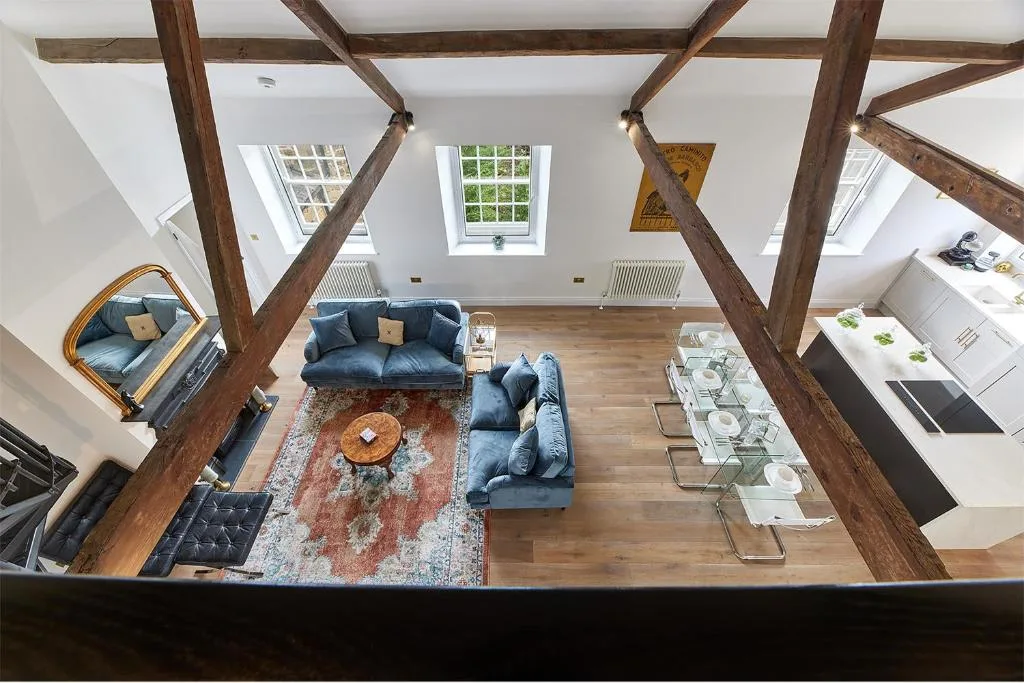 A loft living room with seating, a patterned rug, and a dining table.