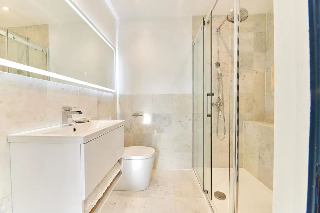 A bright bathroom with a sink, toilet, and glass shower.