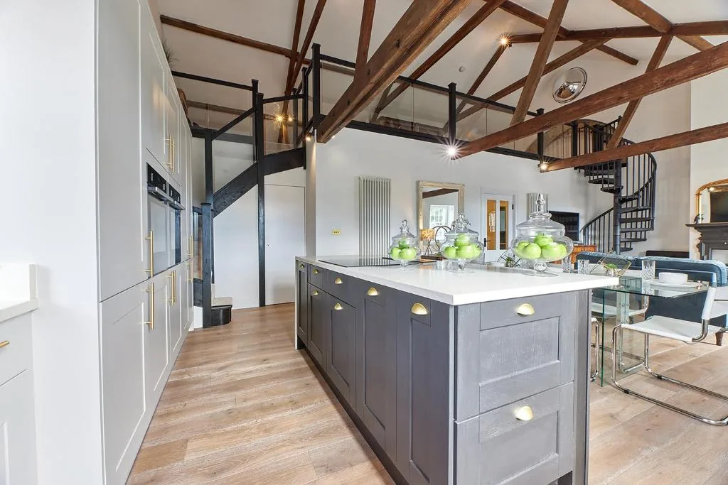 A spacious kitchen with a large island beneath exposed wooden beams.