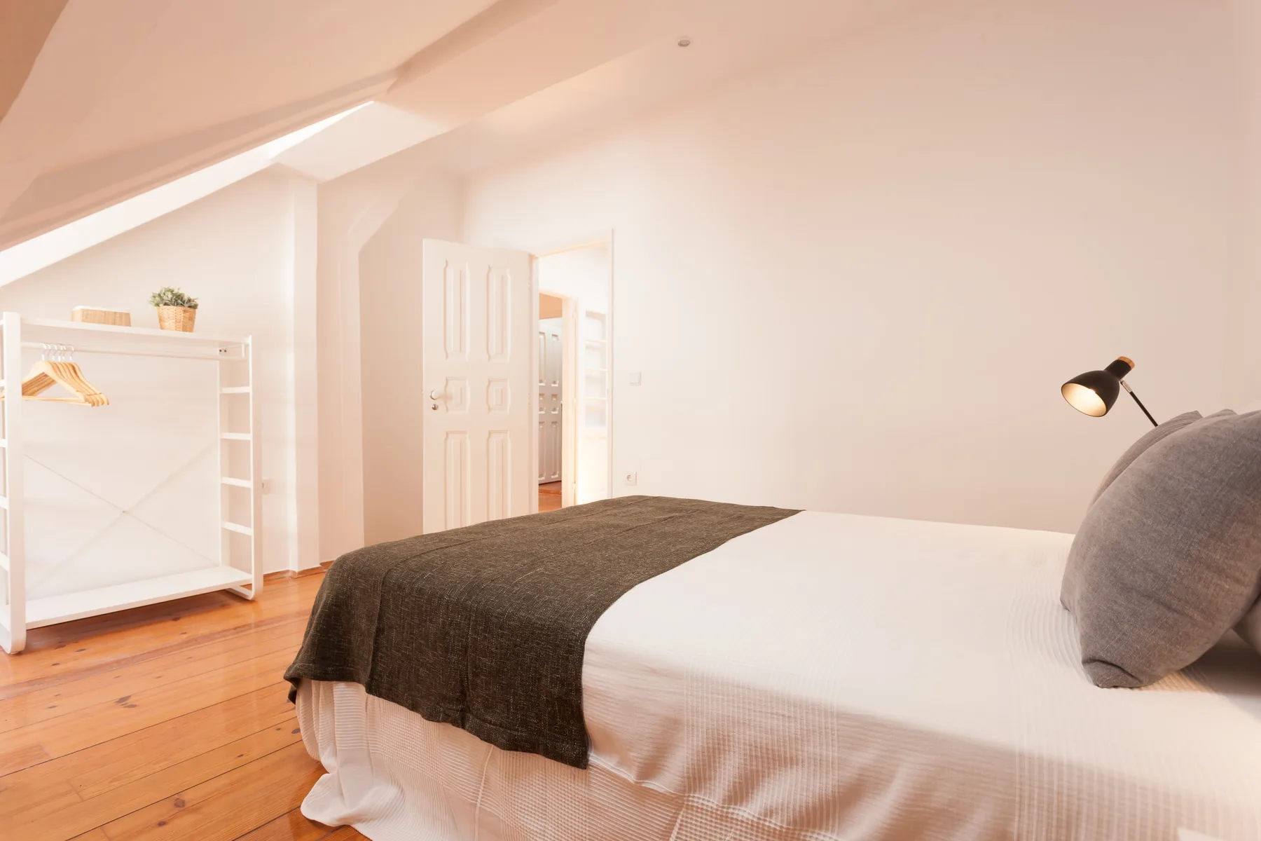 A bedroom with a bed, dark blanket, and open clothing rack.