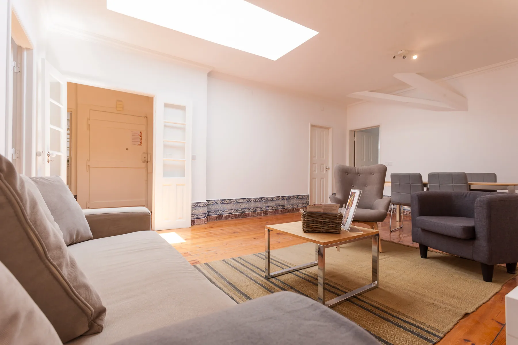 A bright living room with seating, a coffee table, and a large skylight.