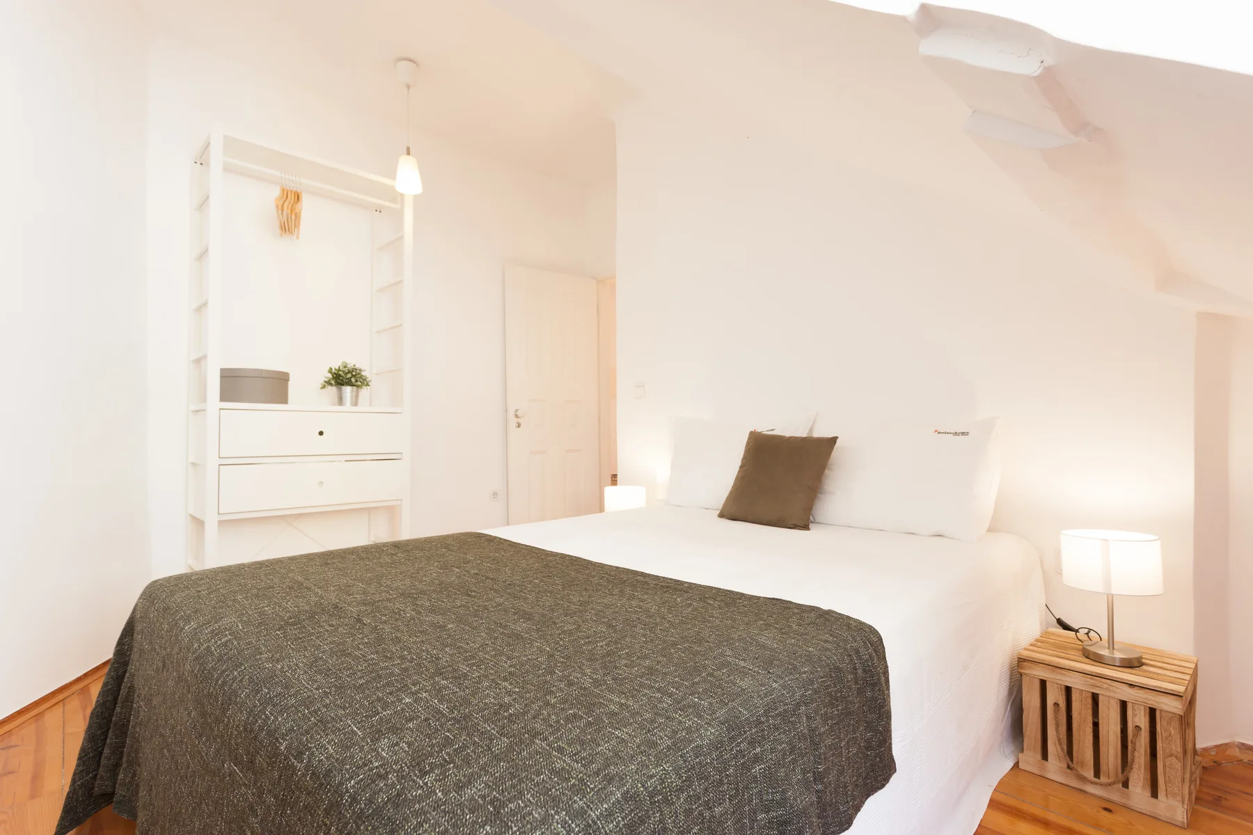 A bedroom with a bed, built-in shelving, and a bedside lamp.
