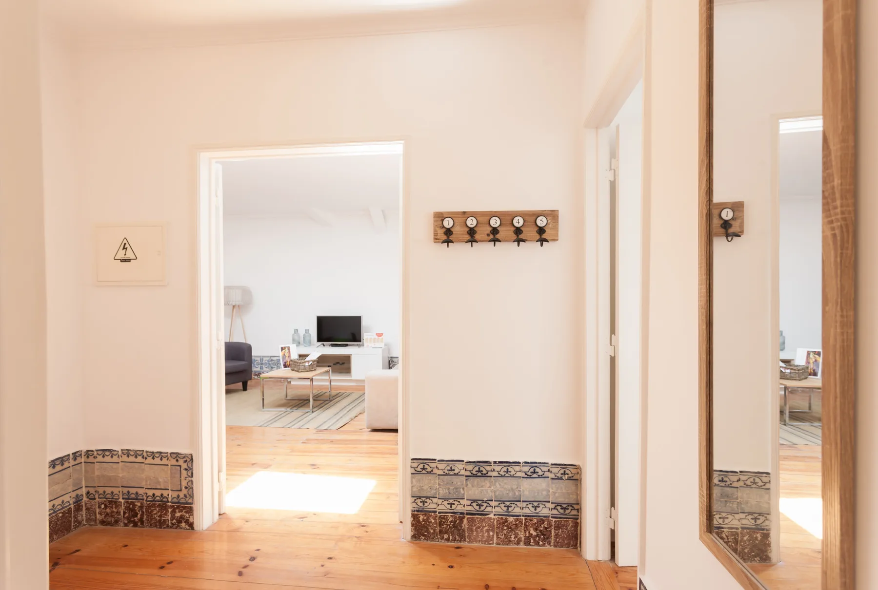 A bright hallway opens into a living area, with patterned tile along the walls.