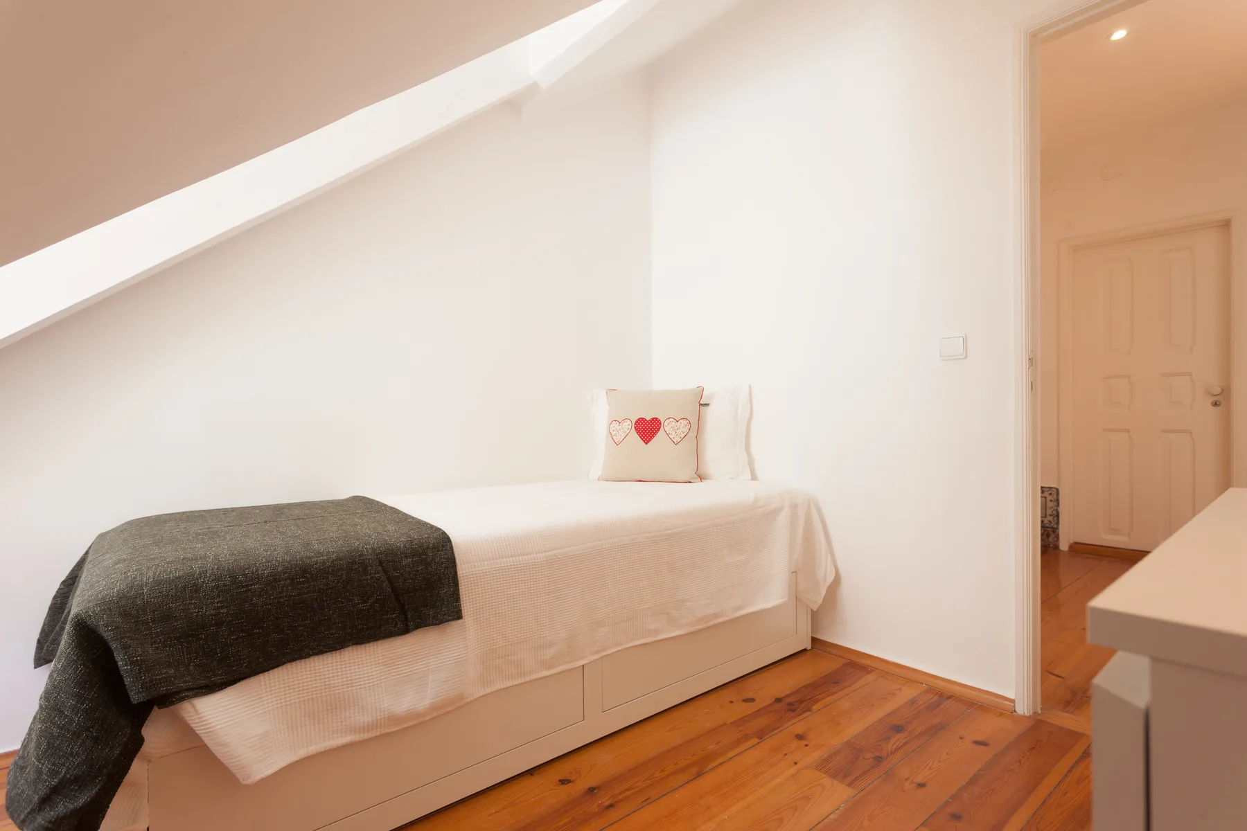 A bedroom with a single bed beneath a sloped ceiling.