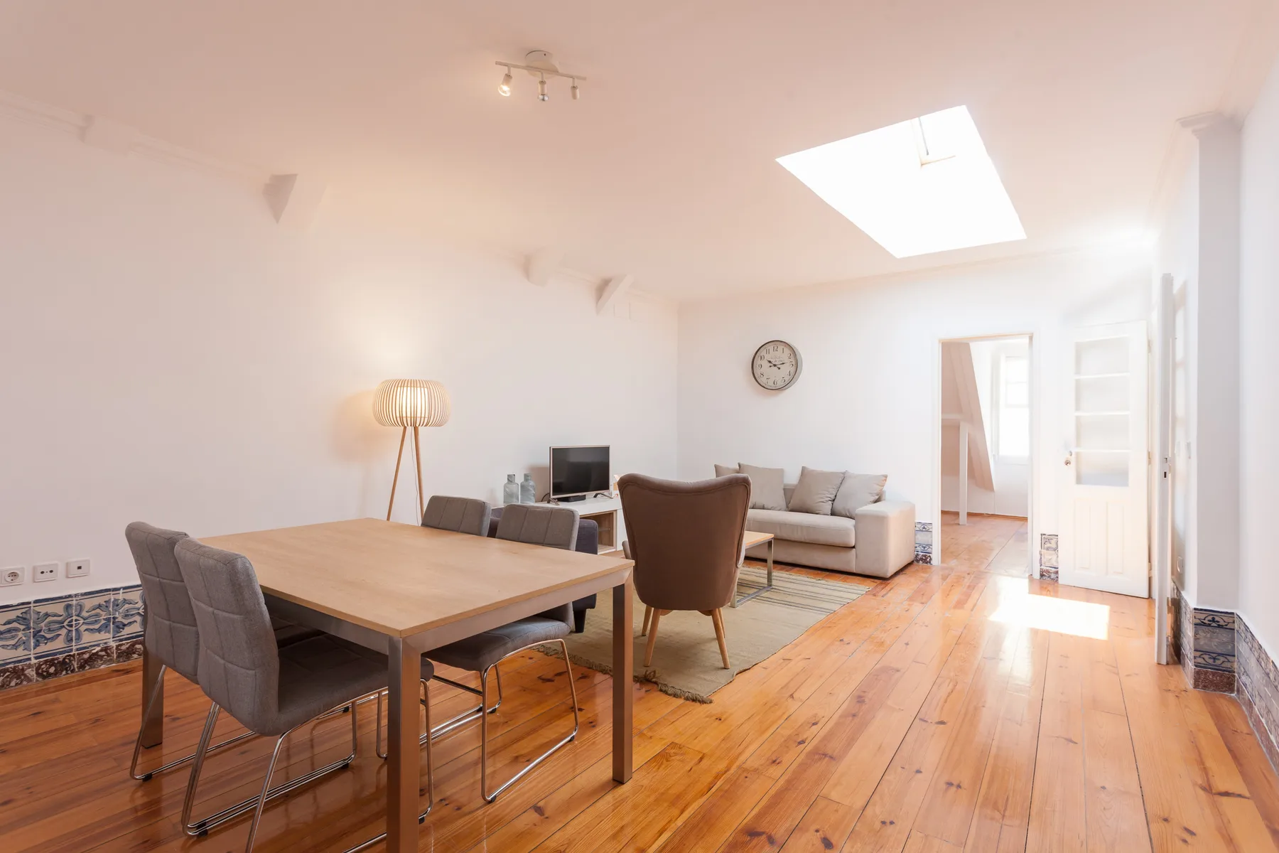 A bright living and dining area with a wooden table and seating.