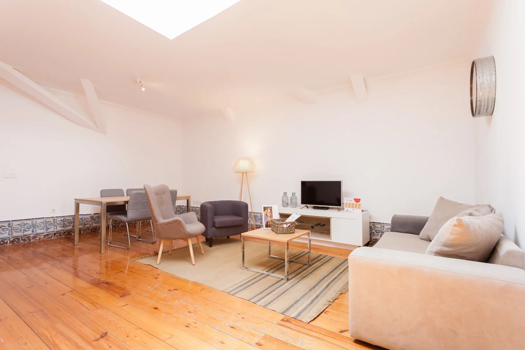 A bright living room with seating, a television, and a dining table.