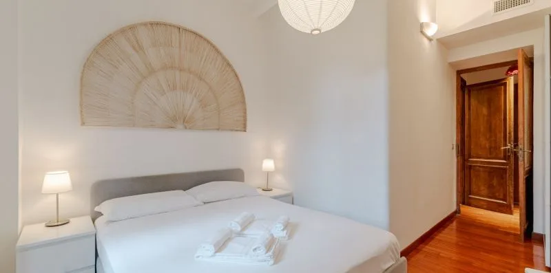 Dormitorio con una cama bien arreglada y un adorno mural en forma de abanico.