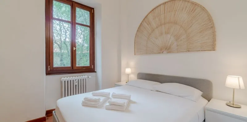Un dormitorio luminoso con una cama bien tendida bajo una decoración tejida de pared.