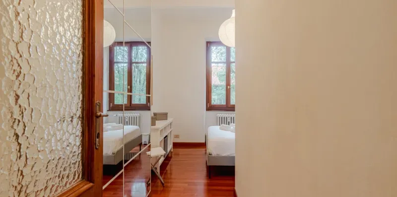 Un dormitorio con dos camas, suelo de madera y ventanas.