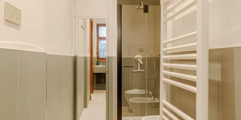 Un baño con una ducha de vidrio y un toallero calefactable de pared.