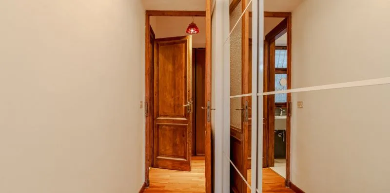 Un pasillo con puertas de madera y un armario con espejo.