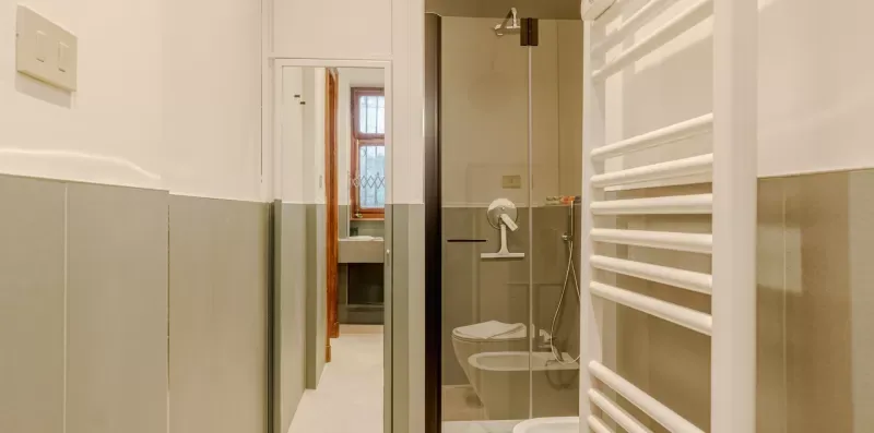 Un baño con una ducha de vidrio y un toallero calefactable.