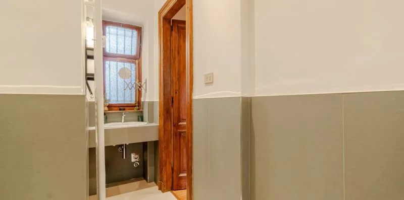 Un baño con un lavabo bajo una ventana y una puerta de madera.