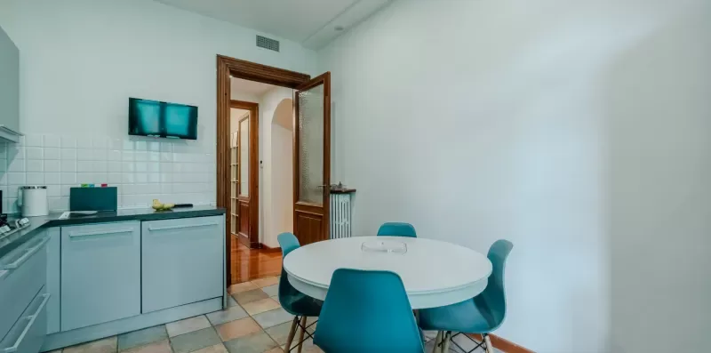 Una pequeña zona de comedor con una mesa redonda y una cocina compacta.