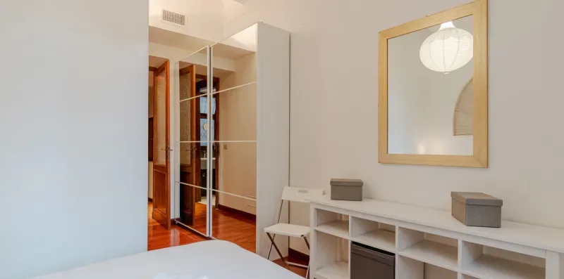 Dormitorio con armario de puertas espejadas y estanterías abiertas.