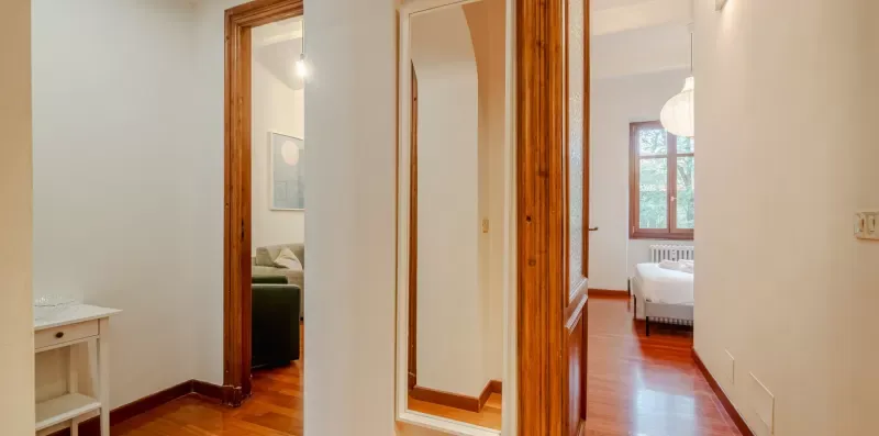 Un pasillo interior luminoso con puertas de madera que dan a habitaciones contiguas.