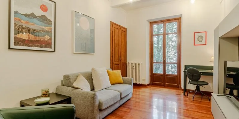 Una sala luminosa con un sofá, cuadros enmarcados y suelo de madera.